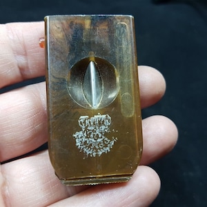 May include: A brown plastic cigar cutter with a silver blade and a white logo that says "Crown" with a crown above the word.