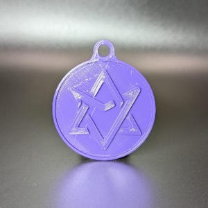 May include: A purple pendant with a geometric design. The pendant is circular with a raised star and diamond shape in the center. It has a small loop at the top for hanging.