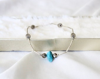 May include: A silver bracelet with a turquoise stone and silver beads.