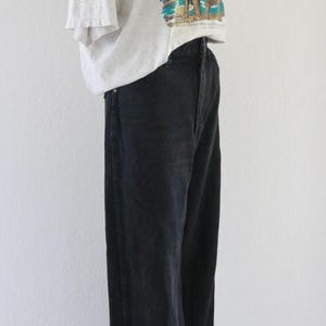 Puede incluir: Una camiseta gris claro con un gr&aacute;fico de mamut, combinada con vaqueros negros y un sombrero de paja. El conjunto se exhibe en un maniqu&iacute;, mostrando un estilo casual y vintage.
