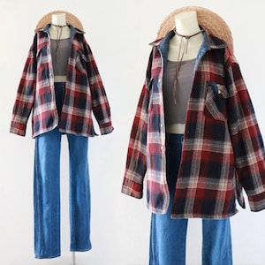 May include: A mannequin displays a vintage outfit. It features a red, navy, and white plaid flannel shirt, a gray crop top, and blue denim jeans. A straw hat and a brown choker necklace complete the look. The outfit is styled for a casual, retro aesthetic.