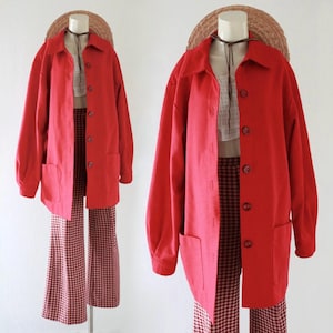 May include: A bright red jacket with a collared neckline and button-up front. The jacket has two front pockets and is paired with checkered pants. A straw hat is on top of the mannequin head.