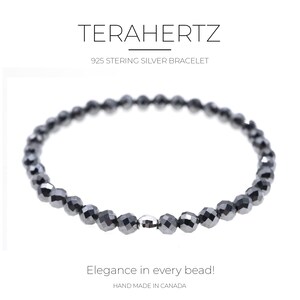 Può includere: Un braccialetto nero con perline e una chiusura argentata. Il braccialetto è realizzato in argento sterling 925 ed è fatto a mano in Canada. Il testo "TERAHERTZ 925 STERLING SILVER BRACELET" è sopra il braccialetto. Il testo "Elegance in every bead! HAND MADE IN CANADA" è sotto il braccialetto.