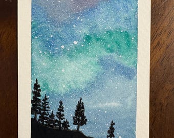 Puede incluir: Una pintura rectangular de acuarela sobre papel que representa un cielo nocturno en tonos azules y verdes, con estrellas blancas salpicadas y la silueta de pinos a lo largo de una línea de horizonte oscura. La esquina inferior derecha incluye el texto 2026.