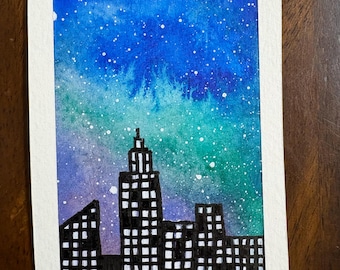 Puede incluir: Una pintura rectangular de acuarela sobre papel que representa la silueta de un horizonte urbano contra un cielo nocturno vibrante. El cielo presenta un degradado de azul, turquesa y morado con salpicaduras de pintura blanca. El texto A 2026 es visible.