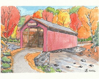 Puede incluir: Una acuarela de un puente cubierto rojo sobre un arroyo. La escena presenta árboles de otoño con follaje naranja y rojo, una base de piedra y un camino que conduce a la entrada. La firma del artista y el año 2026 son visibles en la obra.