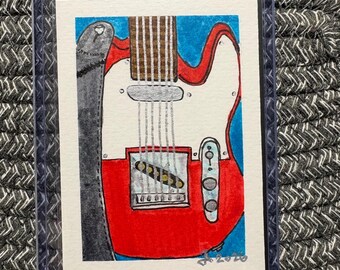 Puede incluir: Una pequeña pintura rectangular en acuarela de una guitarra eléctrica roja con golpeador blanco, herrajes plateados y una correa gris oscuro sobre un fondo azul. La obra está firmada y fechada en 2026 en la esquina inferior derecha y protegida por una funda de plástico transparente.