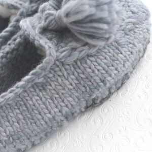 Puede incluir: Pantufla de punto gris con un pomp&oacute;n esponjoso en la parte superior. La pantufla tiene un dise&ntilde;o sencillo y est&aacute; hecha de hilo suave.