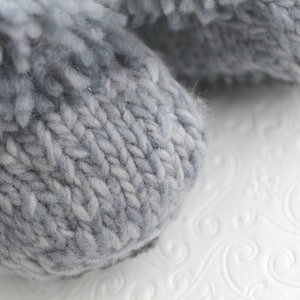 Puede incluir: Primer plano de un par de pantuflas de punto grises con textura peluda.