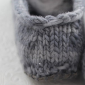 Puede incluir: Primer plano de un par de zapatillas de punto grises con un patr&oacute;n de motas blancas. Las zapatillas est&aacute;n hechas de un material suave y acogedor y tienen un dise&ntilde;o simple y cl&aacute;sico.