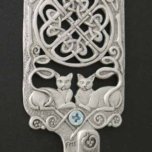 May include: Silver wall hook with a Celtic knot design and two cats on either side. The hook is labeled "FMT".