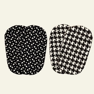 May include: Two sets of black and white patterned oven mitts. One set features a geometric diamond design, and the other has a classic houndstooth pattern. The mitts are made of fabric and are designed to protect hands from heat.