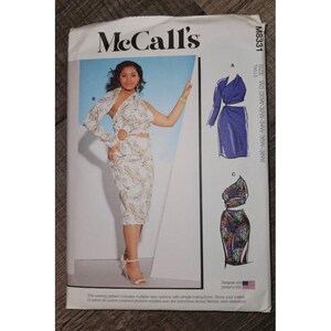 May include: McCall's M8331 sewing pattern envelope featuring a white dress with a gold leaf print, one long sleeve, and a circular cutout at the waist. The envelope displays illustrations of two additional dress variations and lists size W3.