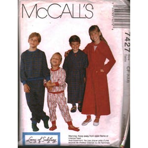 Può includere: Cartamodello McCall's 7427 per pigiami da bambini. La busta mostra un set pigiama a quadri blu, un set pigiama bianco con motivi rossi, una vestaglia a quadri blu e una lunga vestaglia rossa. Il testo include McCall's, 7427 e Lanz of Salzburg.