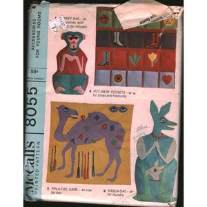 Può includere: Modello stampato McCall's 8055 vintage per accessori per camerette. Il modello include disegni per una borsa a forma di scimmia, tasche portaoggetti, un gioco pin-a-tail (86cm x 91cm) e una borsa kanga (122cm). Il prezzo è 50¢.