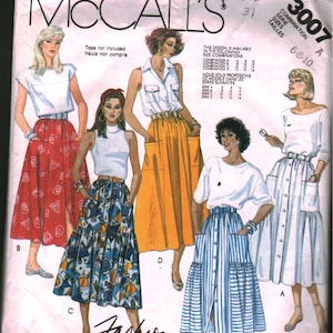 Puede incluir: Sobre de patrón de costura vintage de McCall's con ilustraciones de varias combinaciones de faldas y tops. El sobre muestra el texto "Fashion Basics" y "3007" con opciones de tallas. La paleta de colores incluye blanco, rojo, amarillo y azul.
