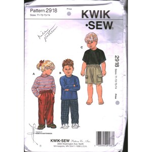 May include: A Kwik Sew pattern envelope 2918 for children's clothing in sizes T1-T4. The front shows three illustrations: a child in a striped turtleneck and red pants, a child in a blue long-sleeve shirt and plaid pants, and a child in a black t-shirt and khaki cargo shorts.