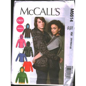 May include: McCall's M6614 sewing pattern envelope for unisex hoodies in size XM (Sml-Med-Lrg). The front displays illustrations of various hoodie styles in colors including pink, blue, green, and camouflage, alongside a photograph of two models wearing hoodies.
