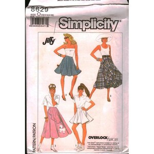 Puede incluir: Patrón de costura Simplicity 8629 con cuatro diseños diferentes de faldas y tops. El patrón incluye un top blanco y una falda azul, una camiseta sin mangas blanca y una falda a cuadros, una camisa blanca y una falda blanca, y una falda rosa con un diseño de caniche.