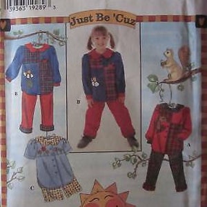 May include: Simplicity sewing pattern for children's clothing. The pattern includes three different outfits: a red and blue plaid shirt with red pants, a blue and white plaid shirt with red pants, and a red and white plaid shirt with brown pants. The pattern is titled "Just Be 'Cuz".