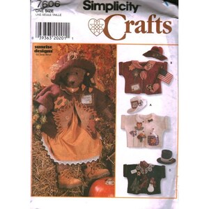 Op de afbeelding: Simplicity Crafts patroon 7606 voor een teddybeer outfit. De verpakking toont een beer met een bruine hoed, jas en oranje geruite jurk, plus drie extra overhemdontwerpen met hoeden, waaronder een met een kleine Amerikaanse vlag patch.