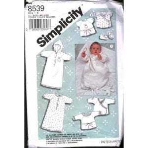 May include: Simplicity pattern for baby sleepwear, featuring various designs including a hooded sleep sack, wrap-style tops, and a nightgown. The pattern includes sizes A and the number 8539. The image shows a baby wearing a sleep sack.