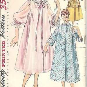 May include: Vintage sewing pattern for a women's robe. The pattern includes three different styles: a long, pink robe with a bow at the neck, a shorter, blue robe with a button-up front, and a yellow robe with a belt. The pattern is printed on paper and includes instructions for sewing the robes.