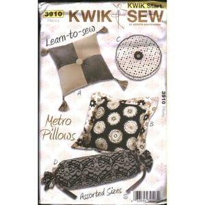 以下が含まれることがあります： Kwik Sew 3910のメトロピロー用型紙封筒。タッセル付きの正方形の枕、水玉模様の丸い枕、花柄の正方形の枕、ダークなダマスク柄の円筒形のボルスター枕の4つのデザインが描かれています。