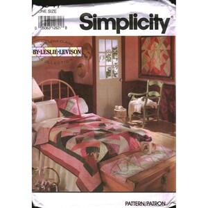 Peut inclure: Une pochette de patron de couture Simplicity de la collection Lena-Claire par Leslie Levison. Le recto présente une photographie d'un lit avec une courtepointe en patchwork géométrique rose et vert, un oreiller assorti et un chemin de lit.