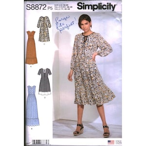 May include: Simplicity sewing pattern S8872 P5 featuring a woman wearing a floral print dress. The pattern includes illustrations of various dress styles. The text "Large fits perfect!" is handwritten on the pattern.