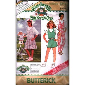 Könnte beinhalten: Vintage Butterick Schnittmuster für Cabbage Patch Kids Outfits. Das Muster zeigt Illustrationen von Kinderkleidung, darunter ein Blumenkleid, ein grüner Overall und ein rosa Overall. Das Muster enthält den Text "YES! IT'S EASY!"