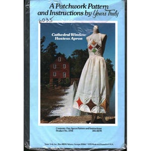 以下が含まれることがあります： 「Cathedral Window Hostess Apron」のパッチワークパターンと説明書のパッケージ。パッケージは青色の背景にテキストとマネキン上のエプロンの画像があります。エプロンにはカラフルなひし形のパッチがあります。