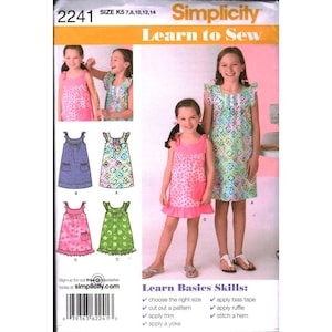 Könnte beinhalten: Simplicity 2241 Learn to Sew Schnittmusterumschlag für die Größen K5 7, 8, 10, 12, 14. Das Cover zeigt Illustrationen und Fotos von ärmellosen Kleidern mit Passe, Rüschen und Taschen in verschiedenen Blumen- und geometrischen Mustern in Pink, Grün und Blau.