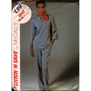 Könnte beinhalten: Ein Schnittmusterumschlag für ein hellblaues zweiteiliges Outfit von McCall's, bestehend aus einer langärmeligen Tunika mit geschlitztem Ausschnitt und einer passenden Hose mit geradem Bein. Die Verpackung zeigt den Text Stitch 'N Save, 8802 und Size A (10-12-14).