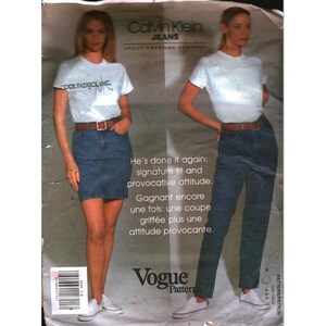 May include: A sewing pattern envelope for Calvin Klein Jeans by Vogue Patterns. The front displays two outfits: a white t-shirt with a denim skirt and a white t-shirt with denim jeans, both featuring brown belts and white trainers.