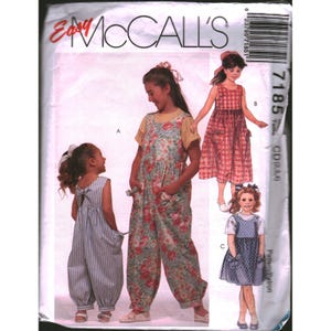 Puede incluir: Patrón de costura McCall's para ropa de niña. El patrón presenta tres conjuntos diferentes: un mono a rayas, un mono floral y un vestido a cuadros. El número de patrón es 7185.