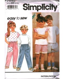 Peut inclure: Patron de couture Simplicity 7892 en taille BB (5-6X) présentant des illustrations et des photos d'enfants portant des hauts, des pantalons et des shorts. Les modèles incluent des motifs à pois et à carreaux, des manches à volants et des ceintures élastiques.