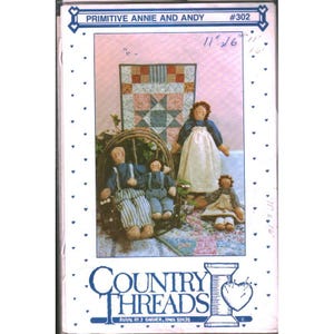 May include: A sewing pattern envelope titled Primitive Annie and Andy #302 by Country Threads. The cover features a photograph of four fabric dolls in blue and white clothing, with one doll in a wooden chair, against a patchwork quilt background.