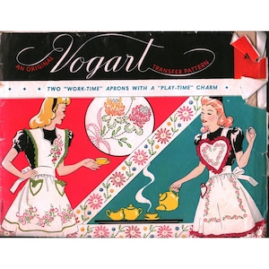 May include: A vintage Vogart transfer pattern envelope featuring two illustrations of aprons with floral embroidery. The design includes text reading An Original Vogart Transfer Pattern and Two Work-Time Aprons With A Play-Time Charm.