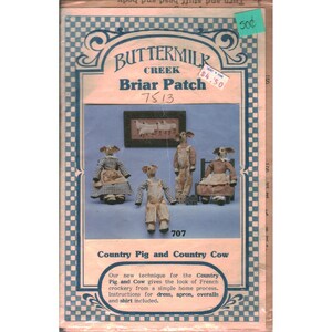 May include: A Buttermilk Creek Briar Patch sewing pattern envelope featuring four anthropomorphic animal dolls dressed in fabric clothing. The cover displays the text Country Pig and Country Cow, 7513, and 707, with a blue and white checkered border.