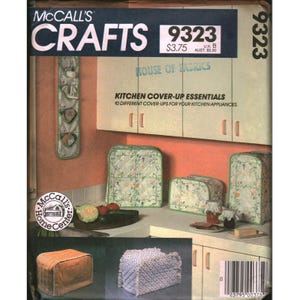Könnte beinhalten: McCall's Crafts 9323 Schnittmusterumschlag für Küchenabdeckungen. Das Cover zeigt Abbildungen von gesteppten Geräteabdeckungen mit Blumen- und Streifenmustern, darunter ein Hängeorganizer sowie Abdeckungen für Toaster und Küchenmaschine.