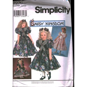 May include: A Simplicity sewing pattern envelope 9970 for Daisy Kingdom dresses. The cover features illustrations of dresses with puff sleeves, lace collars, and floral patterns, along with a matching doll outfit. Includes size range HH 3, 4, 5, 6.