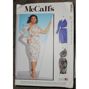May include: McCall's M8331 sewing pattern envelope for size W2 (20W-28W). The front displays a model wearing a white dress with a gold leaf print, featuring a one-shoulder design and a circular cutout. Includes illustrations for styles A and C.