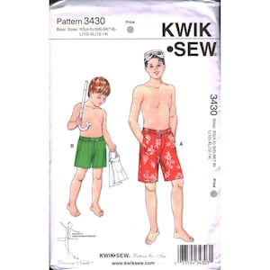 May include: A sewing pattern for boys' swim trunks, featuring illustrations of two boys wearing different styles of shorts. The pattern includes sizes XS(4-5) to XL(12-14). The shorts are red with a floral design and green.