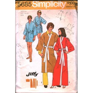 Pode incluir: Um envelope de molde de costura Simplicity 5685 com ilustrações de quatro pessoas vestindo vários estilos de roupões. A capa exibe o texto 5685 Simplicity, Jiffy e informações de tamanho, com notas manuscritas visíveis no papel.