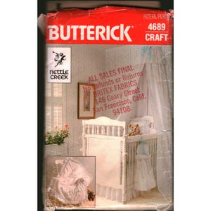May include: A Butterick craft pattern for a baby crib set. The cover features a white crib with a canopy, a teddy bear, and a matching blanket. The pattern number is 4689.