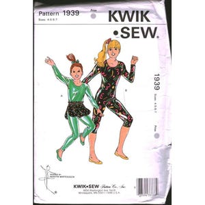 May include: Kwik Sew pattern 1939 for sizes 4-5-6-7. The envelope features illustrations of two outfits: a solid green long-sleeve leotard with a black polka-dot skirt, and a black long-sleeve unitard with a colorful abstract pattern of shapes.