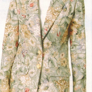 Può includere: Una donna indossa un blazer con motivo floreale con bottoni dorati e una gonna bianca. Il blazer ha uno sfondo verde con fiori rosa, bianchi e gialli.