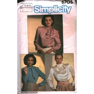 Op de afbeelding: Simplicity naaipatroon 6705 met drie blouse-ontwerpen. De blouses hebben lange mouwen en verschillende halslijnen, waaronder een strik, een hoge kraag en een sleutelgat. Het patroon bevat maten 16, 18 en 20. De blouses worden getoond in roze, blauw en wit.