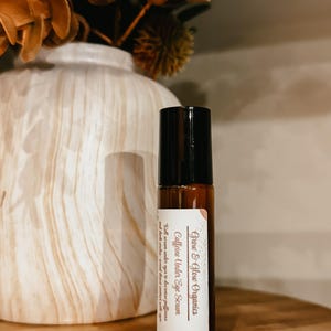 K&ouml;nnte beinhalten: Eine braune Glasrollflasche mit schwarzem Verschluss und einem wei&szlig;en Etikett mit der Aufschrift "Grow & Glow Organics Caffeine Under Eye Serum Roll serum under eyes to decrease puffiness and dark circles. A good boost for almost any skin."